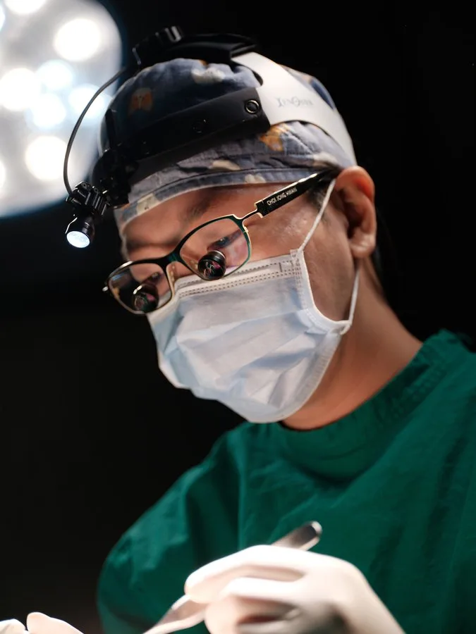 Dr. Jonghwan Choi đang mổ với kính lúp phẫu thuật và đèn đội đầu